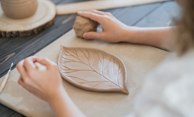 Woman decorating handmade pottery plate close-up