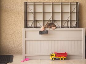 Young boy playing with his toys hiding in a storage bin