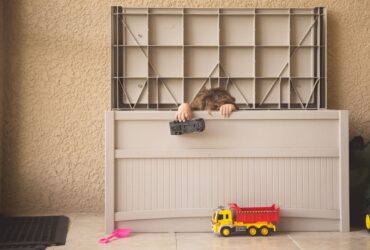 Young boy playing with his toys hiding in a storage bin