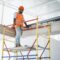 Young handsome builder climbing on scaffolding at construction site