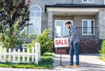 young man with sale board selling his new house