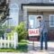 young man with sale board selling his new house