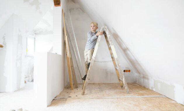 Boy standing on ladder in attic to be renovated