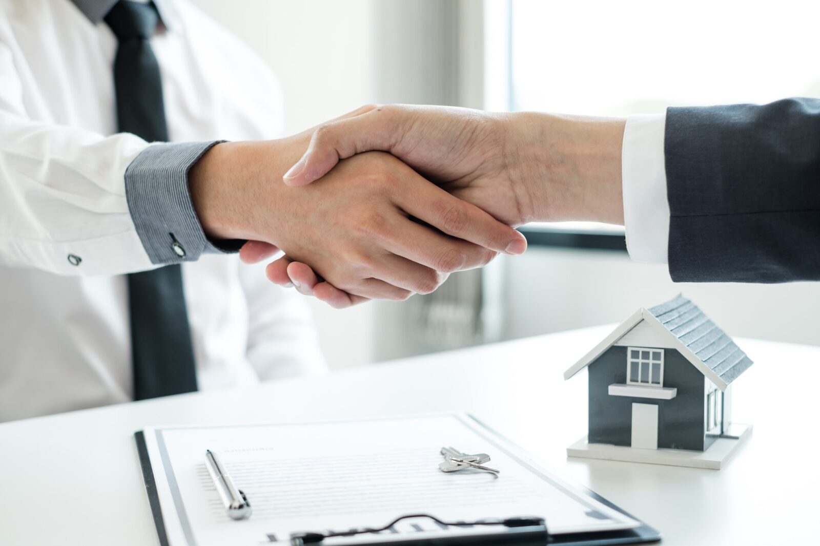 Businessmen and brokers' real estate agents shake hands after completing negotiations to buy houses