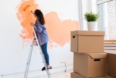 Cheerful woman painting the walls of new home. Renovation, repair and redecoration concept