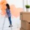 Cheerful woman painting the walls of new home. Renovation, repair and redecoration concept