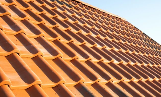 Overlapping rows of yellow ceramic roofing tiles covering residential building roof