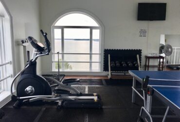 Sport training equipment in a home gym, elliptical cross trainer, ping pong table, indoor gym, home