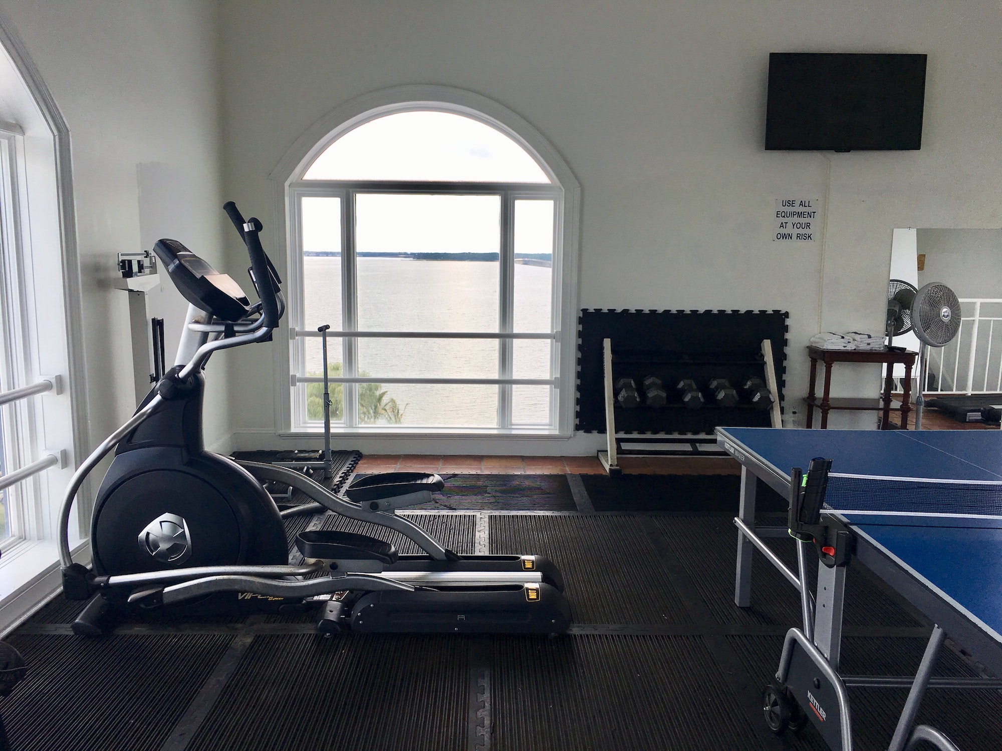 Sport training equipment in a home gym, elliptical cross trainer, ping pong table, indoor gym, home