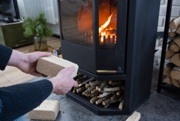 Hands kindle the hearth with economical briquettes