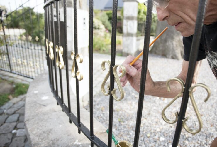 close up a man paints a fence in gold paint, metal restoration, Do it yourself