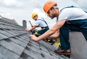 selective focus of handsome handyman repairing roof with coworker