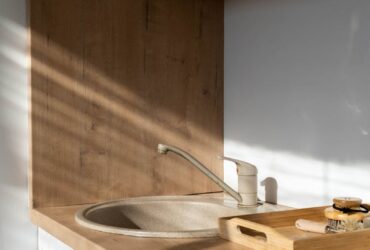 A modern minimalist kitchen showcasing a wooden sink area with natural sunlight.