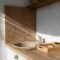 A modern minimalist kitchen showcasing a wooden sink area with natural sunlight.