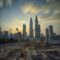 Dramatic view of the Petronas Towers towering over a busy construction site in Kuala Lumpur at sunset.