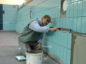 Tiler expertly aligns ceramic tiles on a swimming pool wall. Indoor construction setting in Wrocław.