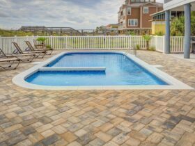 Relaxing poolside patio with sun loungers and villas, perfect for a summer retreat.