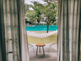 Charming poolside view through curtains with hammock and seating, ideal for a summer vacation.
