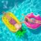 Two boys sunbathing on colorful pool floats, enjoying a sunny day in a clear blue swimming pool.