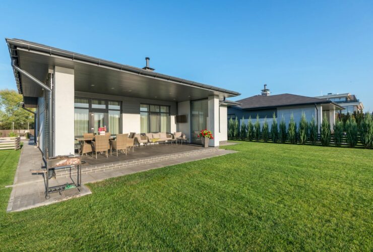 A modern house with a wide patio and neatly landscaped backyard, ideal for real estate and architecture themes.
