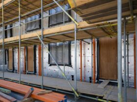 Scaffolding at a residential building under construction with windows and insulation sheets visible.