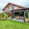 Residential cottage with balcony and opened veranda opening view on lawn and trees growing in backyard