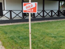 A modern house with a sold sign on a grassy lawn, indicating property purchase.