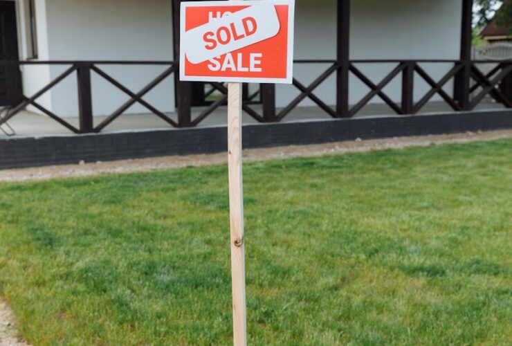 A modern house with a sold sign on a grassy lawn, indicating property purchase.