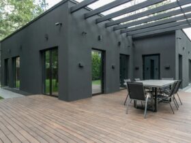 Contemporary black house with spacious wooden terrace and outdoor seating area.