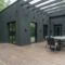 Contemporary black house with spacious wooden terrace and outdoor seating area.