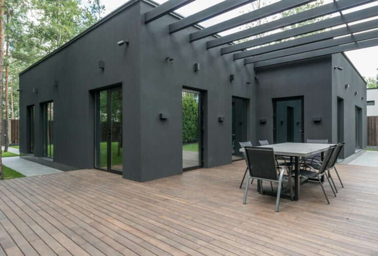 Contemporary black house with spacious wooden terrace and outdoor seating area.