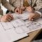 People discuss architectural plans in a real estate planning session, highlighting teamwork.
