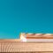 A serene image of terracotta roofs contrasting with a vibrant blue sky, showcasing architectural simplicity.