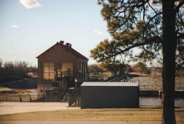 Charming view of a historic building near Lake Overholser Dam, Oklahoma City, with clear skies and lush greenery.