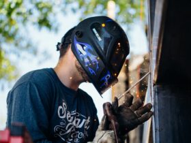 A skilled welder working outside, producing sparks. Shows focus and safety.