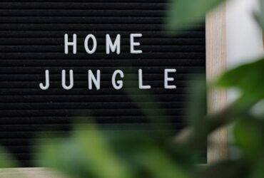 Cozy home decor with 'Home Jungle' sign amidst vibrant green houseplants creating a relaxing indoor atmosphere.
