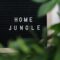 Cozy home decor with 'Home Jungle' sign amidst vibrant green houseplants creating a relaxing indoor atmosphere.