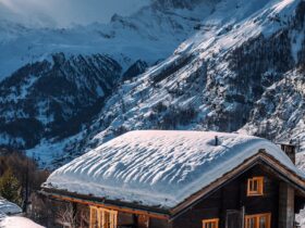 Charming snow-covered chalet set in a serene alpine mountain winter scene.