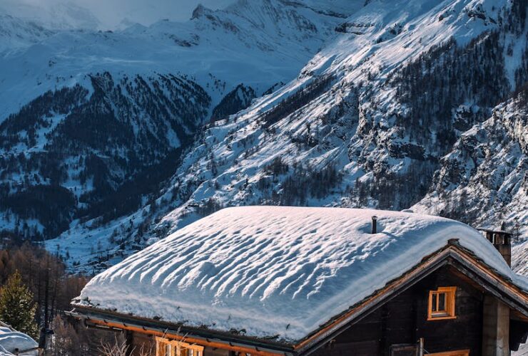 Charming snow-covered chalet set in a serene alpine mountain winter scene.
