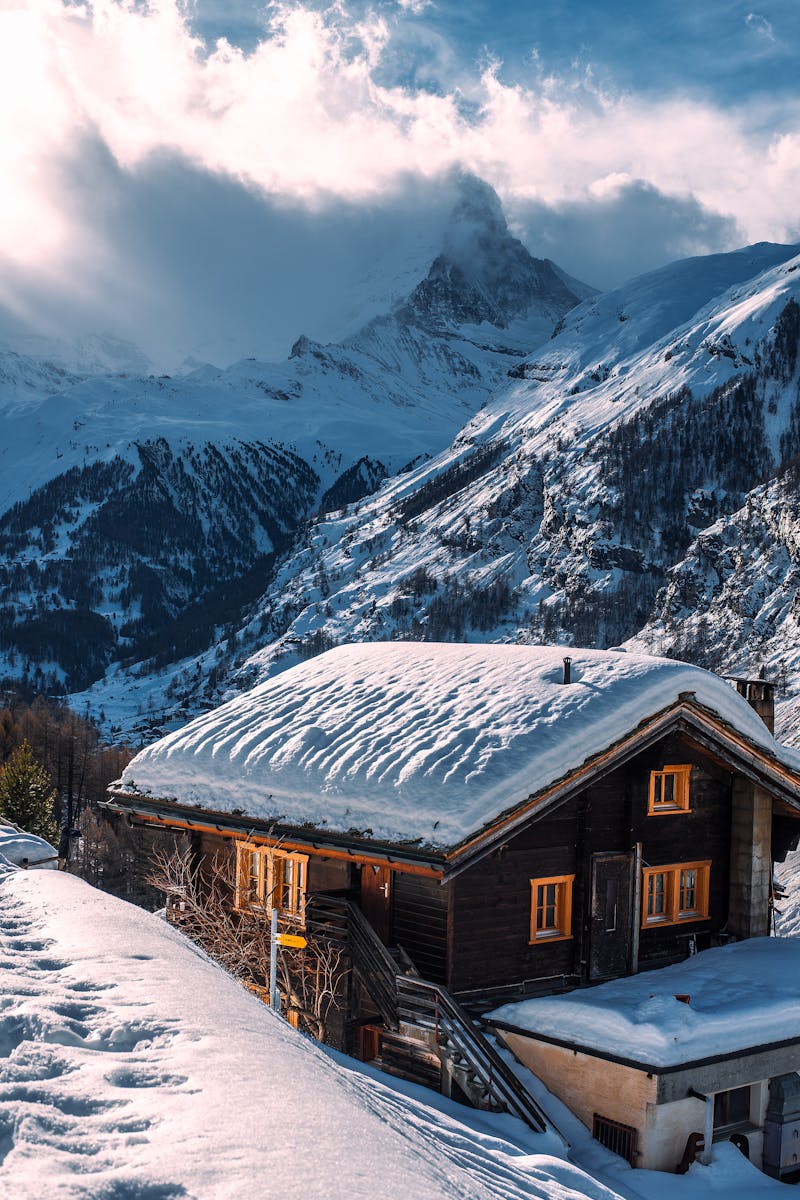 Charming snow-covered chalet set in a serene alpine mountain winter scene.