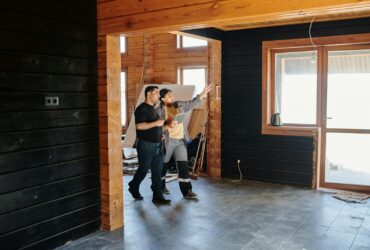 Two adults discussing home renovation in a partially constructed modern wooden interior.