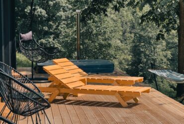 Wooden deck with lounge chairs surrounded by lush greenery, perfect for relaxation.