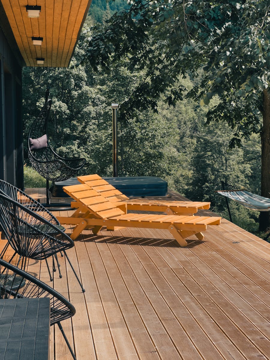 Wooden deck with lounge chairs surrounded by lush greenery, perfect for relaxation.