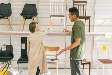A couple explores chair options together in a modern furniture store during the day.