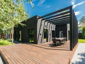 Stylish outdoor space with wooden deck and dining set, surrounded by lush greenery.