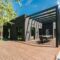 Stylish outdoor space with wooden deck and dining set, surrounded by lush greenery.