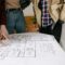 Group of people reviewing a blueprint for real estate planning. Collaborative discussion indoors.