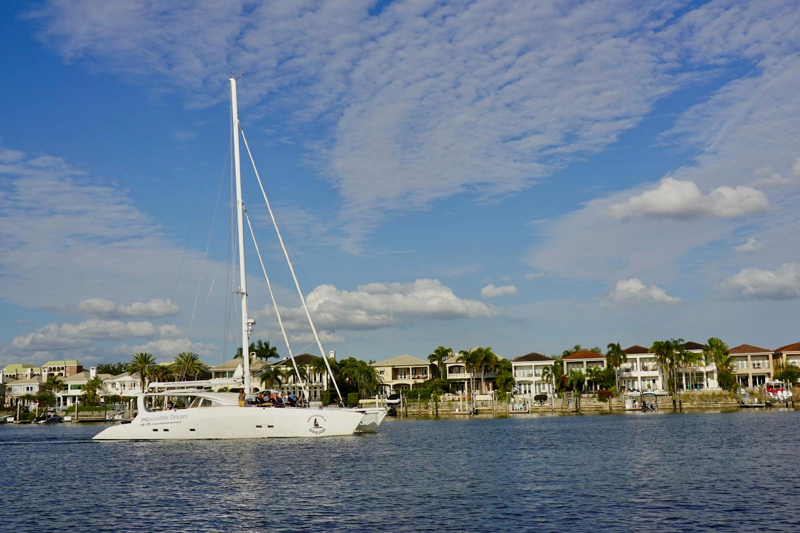 Yacht cruising in scenic Tampa Bay with waterfront homes and clear skies.