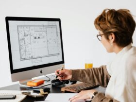 Side view of anonymous female employee in casual clothes and eyeglasses writing out information from computer while working at table in modern light office