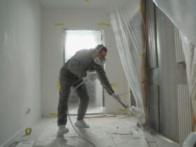 A worker in protective gear painting walls during an indoor renovation project.